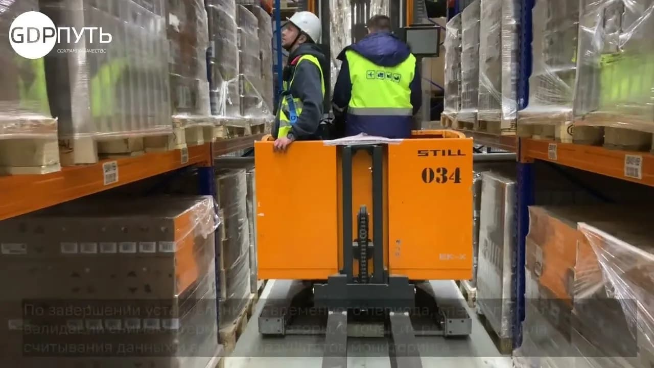 Кадр из ролика: специалисты устанавливают терморегистраторы в узком проходе склада